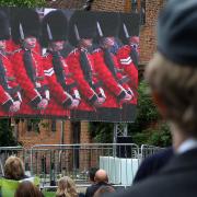 A man in military uniform watches the Queen's state funeral, which was shown on a big screen at Hatfield House
