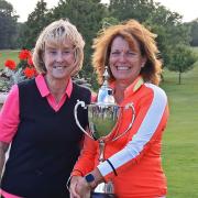 Michelle Gardner being presented with the ladies' club championship trophy by club captain Lesley Hewitt.