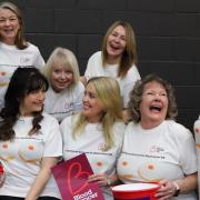 Potters Bar Theatre Company's Calendar Girls cast having a laugh with their collection buckets and bun T-shirts.