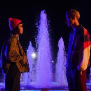 Callina Liang as Mei and  Eden H. Davies as Jonny in new ITVX teen drama Tell Me Everything in a scene filmed in Letchworth, Hertfordshire, by the Broadway Gardens Fountain.
